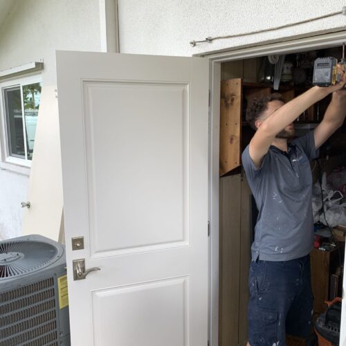 a professional contractor from mister window is installing the door to a house.